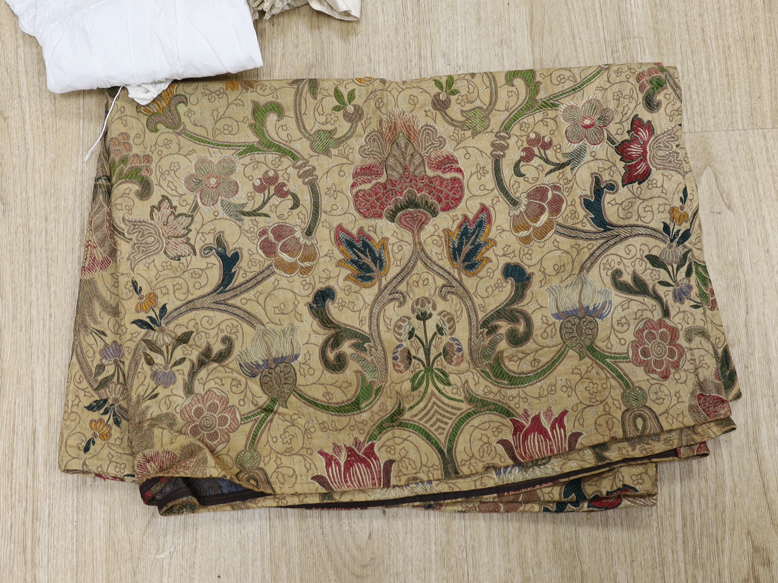 An embroidered Indian felt cover, a cream satin pageboy outfit, a white work christening gown, a silk shawl, a knitted silk shawl and a length of brocade